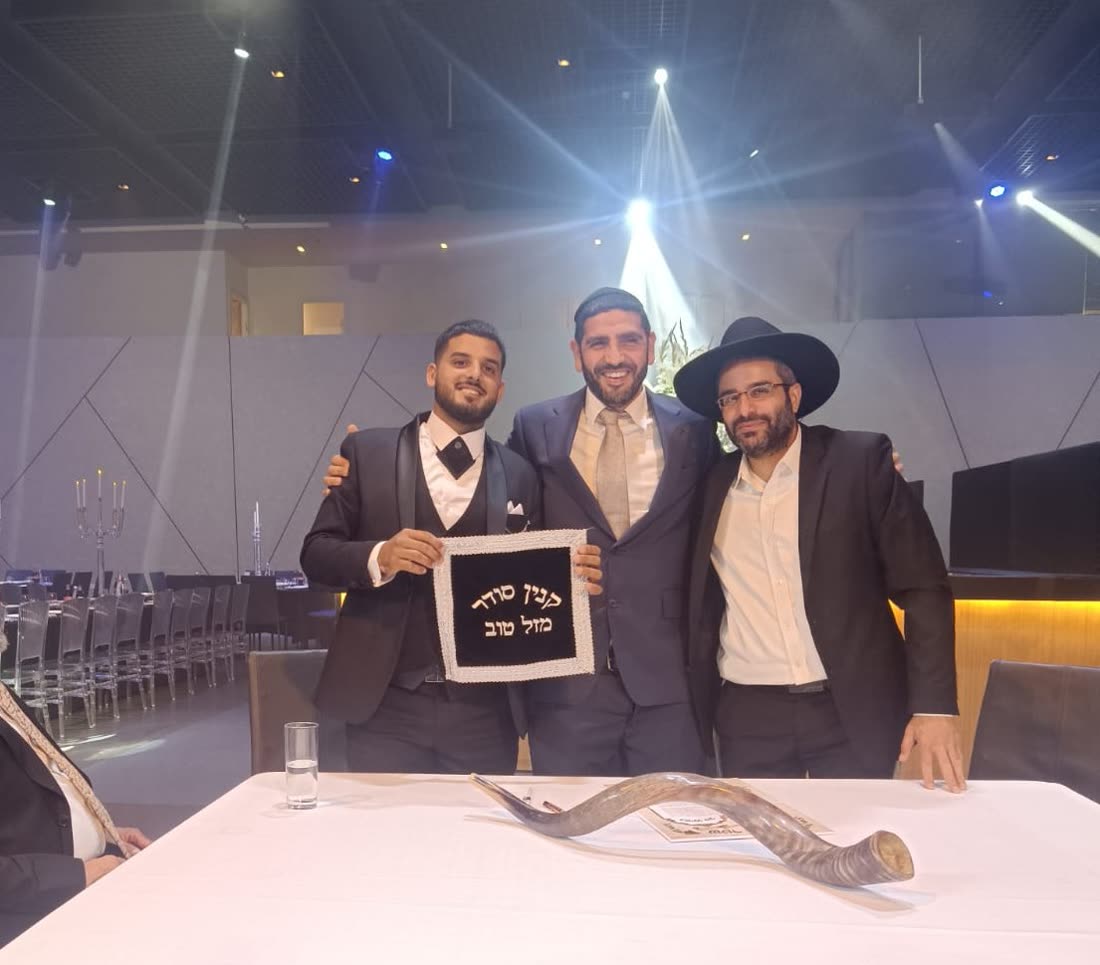 דיוקן של הרב חיים חורי — מחייך, בחליפה כחולה ועניבת שמפניה